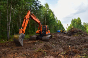 Excavator clearing forest for new development. Tracked heavy power machinery for forest and peat industry.